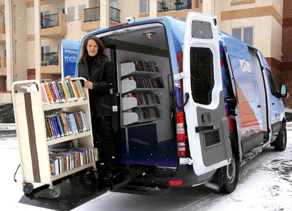 Lobby Stops van driver Lisa Ward shows that even snowfall can�t prevent a rack of books from being lowered on the 
electronic lift, preparatory to being wheeled into one of the 15 assisted-living locales on her route � in this case the Village at Skyline on the Westside.
Westside Pioneer photo