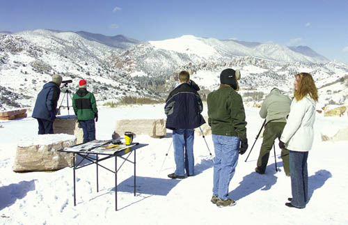 With supervision from Division of Wildlife volunteers Jodi
Hendrickson (foreground, far right) and Debbie Ackley
(facing her), people use telescopes to view several of the
animals that were grazing that morning above Glen Eyrie 
during the Bighorn Sheep Festival Feb. 18. The telescopes
are looking northwest from the overlook on Mesa Road. The
bighorns are part of the Rampart Herd that lives near the Garden of the Gods.
Westside Pioneer photo
