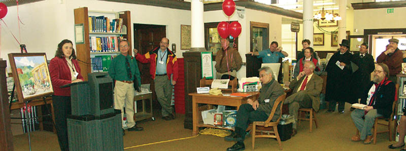 With artist Jack Ekstrom standing to her left and his painting
(Old Carnegie Library in Old Colorado City) to her right,
Old Colorado City Branch Manager Julianne Rist talks about 
the librarys fund-raising drive March 6. Seated at the table 
in the middle foreground is Pikes PeakLibrary District 
Director Jose Aponte and (to his right) Library Campaign 
Committee member Chuck Murphy. Standing to the left of 
Ekstromis Committee President Jack Beal, and hidden 
slightly behind the balloon strings is Councilman Jerry Heimlicher.