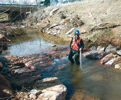 Stream consultant Pete Gallagher stands beside a V-shaped
drainage structure he and his crew built in Fountain Creek 
behind the under-construction Anglers Covey fly fishing store.