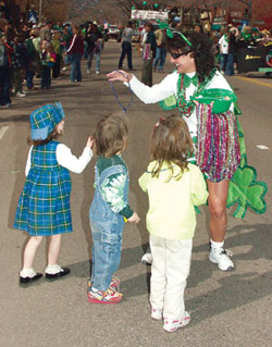 A marcher from one of the Area Labor 
Council floats hands out jewelry to young parade-goers.