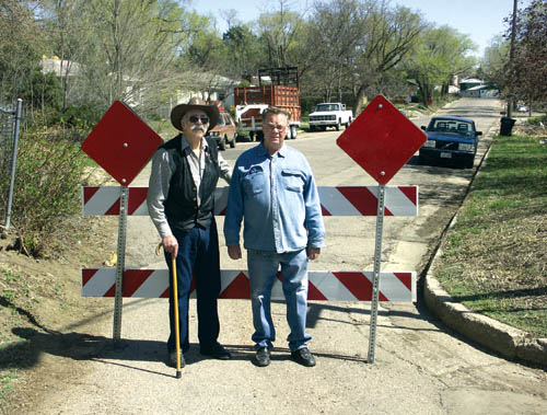 Fred Bishop (left) and Steve Webb stand in front of the
barricade that City Traffic Engineering recently bolted into
the pavement to block a narrow, long-time access to their 1700 block of St. Vrain Street.
Westside Pioneer photo