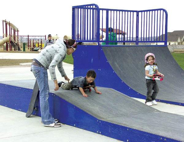 Teryn Guadagnoli helps her son Jace ride down a ramp at
the new Gold Camp Park skate area while Madison Moore (in
helmet) looks on. In the background can be seen the parks playground and some of the sod that was recently laid. 
Westside Pioneer photo