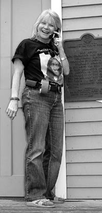 Standing on the front steps of the Bancroft cabin, event
organizer Lynda Dunne is clad in Territory Days �battle
dress� � including sneakers, this year�s festival T-shirt, cell phone and duct tape.
Westside Pioneer photo
