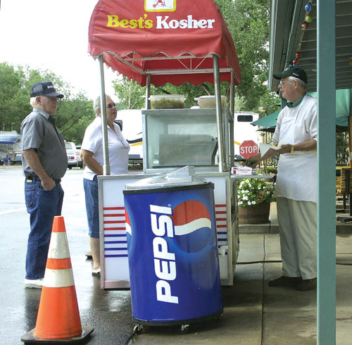 Chuck Murphy (far right) serves hotdogs from the outdoor concession stand at the campground on a weekend 
evening last August.
Westside Pioneer photo