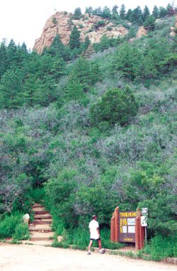 A jogger stretches in front of the Section 16 Trailhead sign. The county-maintained trailhead provides non-motorized 
access to the 640-acre property - a rock formation of which can be seen looming above.
