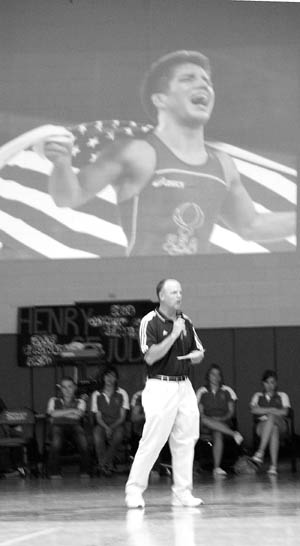 With an image from Henry Cejudo�s Olympic Games gold medal  celebration projected on the wall behind him, 
Coronado High wrestling coach Matt Brickell praises the athlete � whom he coached during the 2006 graduate�s two
years at the school � during an all-school assembly in the gymnasium Aug. 22. �He chose to do the right thing and now he�s golden,� Brickell said.
Westside Pioneer photo