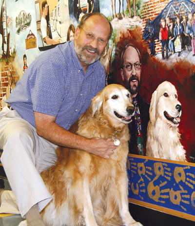 Bristol Principal Steve Ferguson dutifully poses with his dog
Tigger next to the painting of themselves in the 54-foot-long mural that was created on a school wall by the late Kathy Halstead Barnes in 2000. An inside joke is the 
elf Barnes painted onto Ferguson�s tie � a reminder of his dress-up character every Christmas at the school.
Westside Pioneer photo