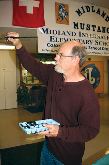 Fred Eyer puts finishing touches on his IB attitudes/profiles mural in the Midland Elementary lobby. He drew the globe 
and hands and created the caricatures for each attitude, while the profiles were clipped and positioned at the top. In the background, over his left shoulder, is part of 
his mural that�s become the new Midland logo.
Westside Pioneer photo