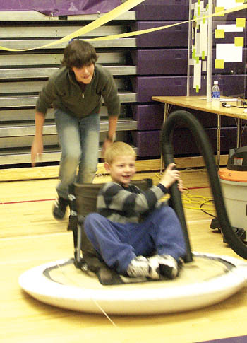 West student Alex Killian gives a young citizen a push to get
started on his homemade hovercraft at the West Science
Fair Nov. 30. Note how the device is connected to a power
vacuum for the needed air.
Westside Pioneer photo